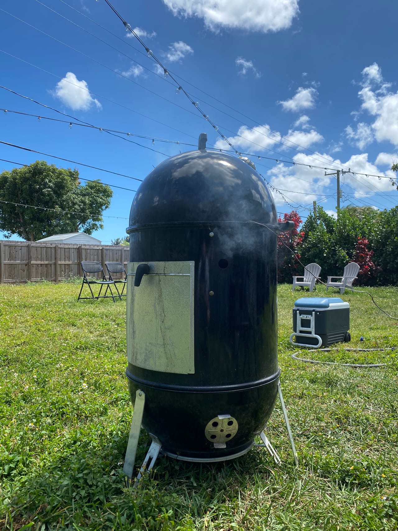 The original 22-inch Weber Smokey Mountain smoker where Apocalypse BBQ began in 2020, smoking in a Kendall backyard
